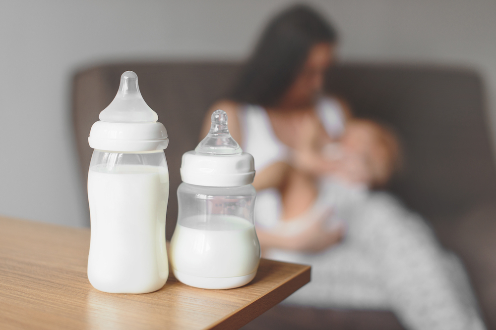 Bottles,With,Breast,Milk,On,The,Background,Of,Mother,Holding